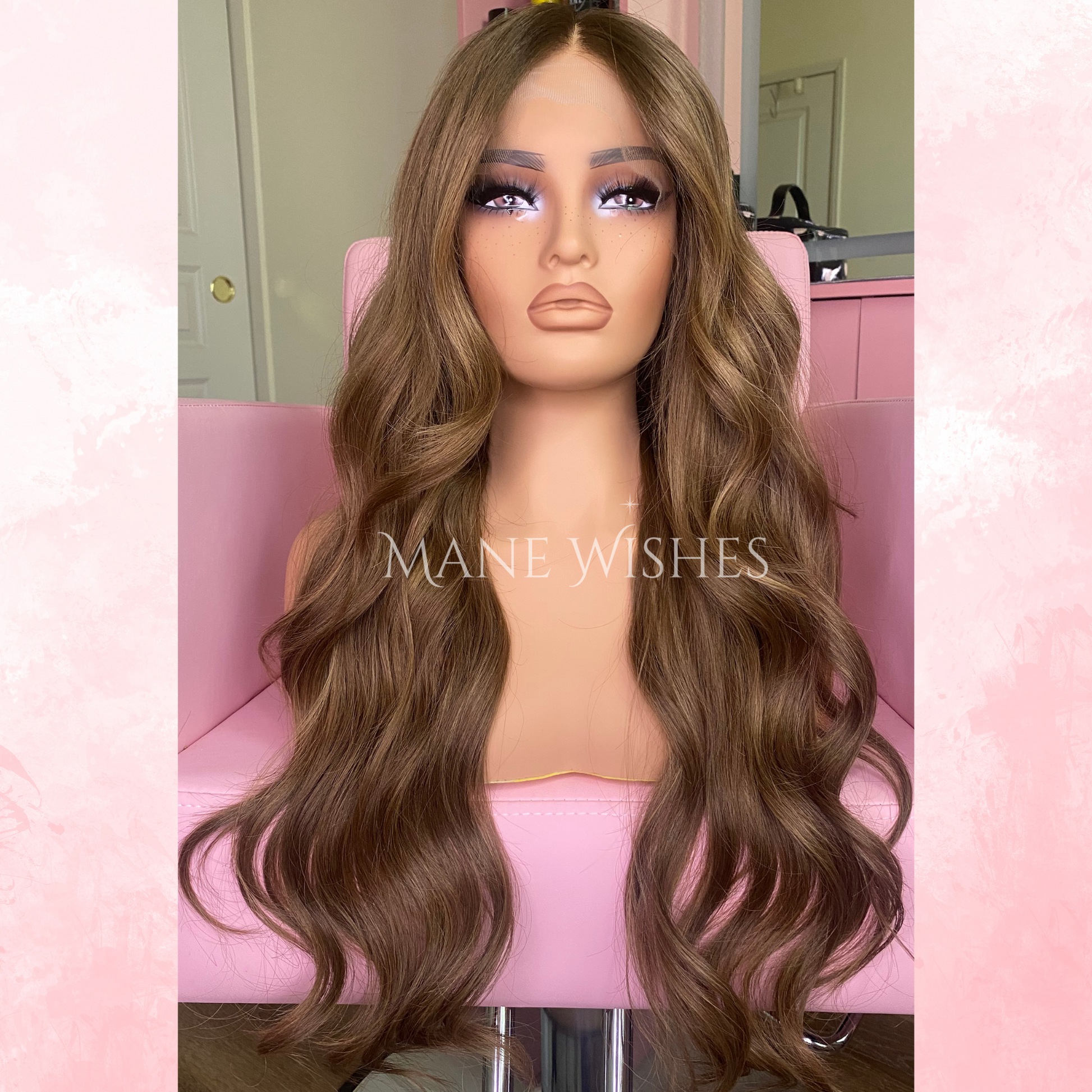 Mannequin head with long brown wavy hair on a pink chair, branded 'Mane Wishes'.
