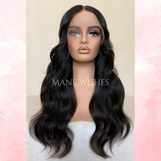 Mannequin head with long black wavy hair on a pastel pink and beige background, branded 'Mane Wishes'.