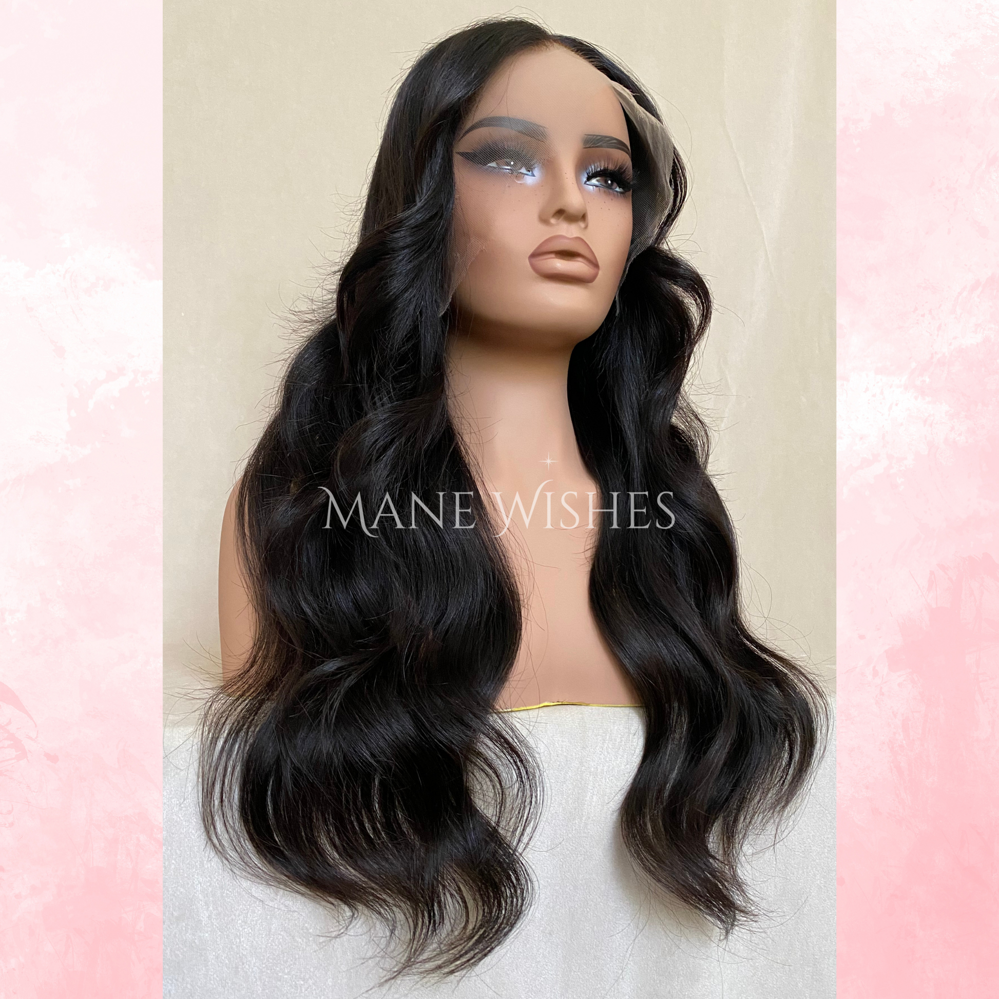 Mannequin head with long black wavy wig on a pastel pink and beige background, branded 'Mane Wishes'.