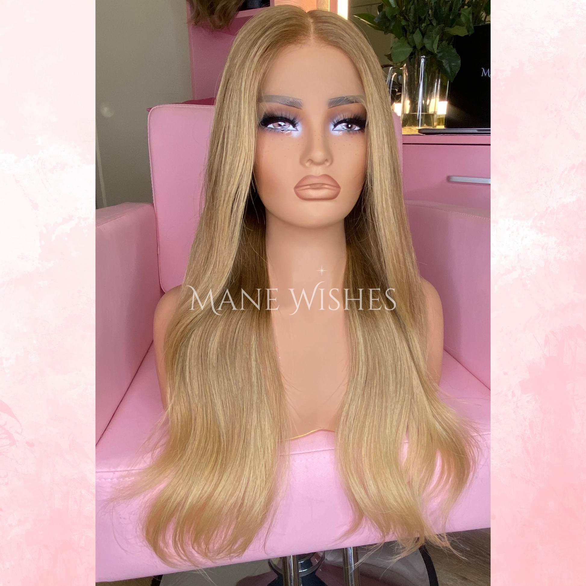 Blonde wig on a mannequin head with 'Mane Wishes' branding, set against a pink background.