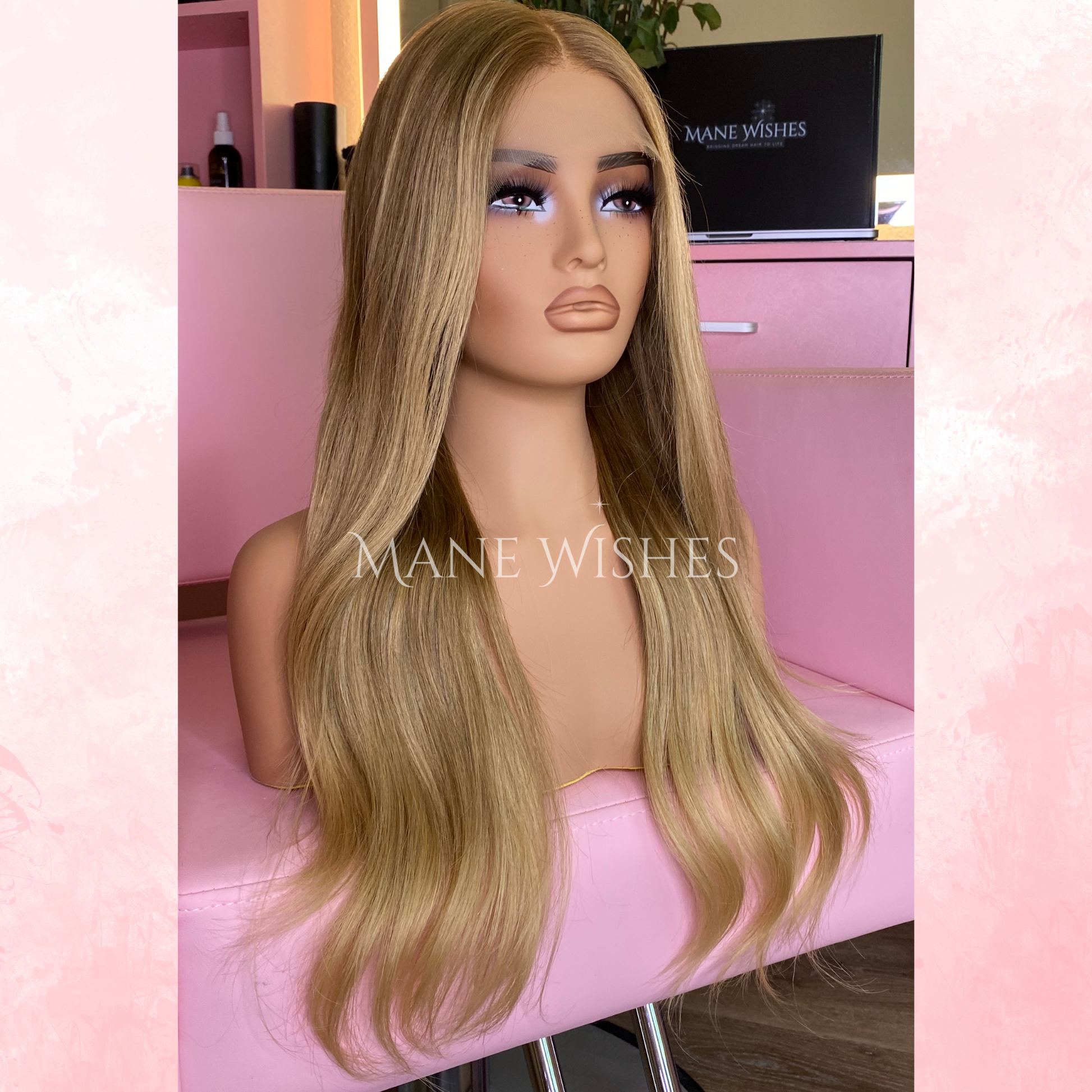 Blonde wig on a mannequin head with 'Mane Wishes' branding in a salon setting.