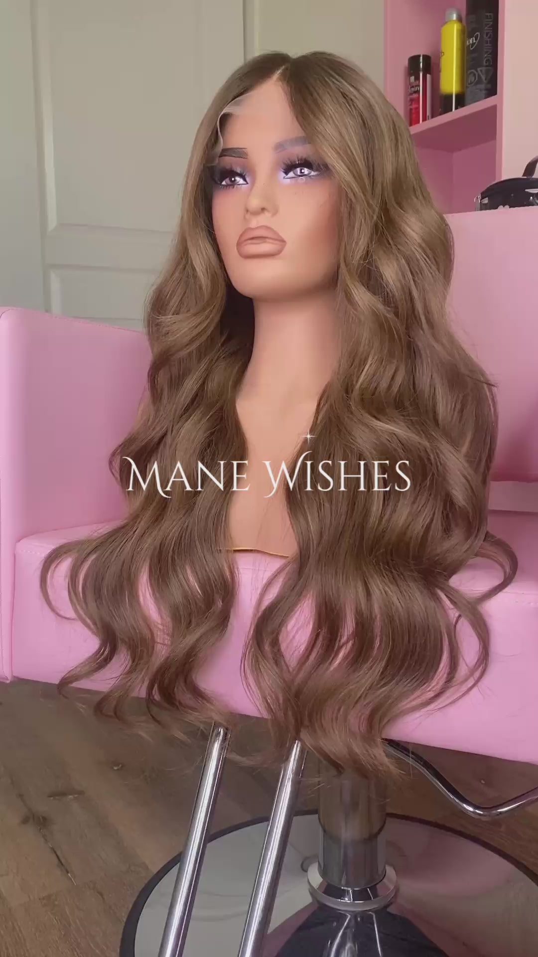 Mannequin head with long brown wig on a pink chair, branded 'Mane Wishes'.