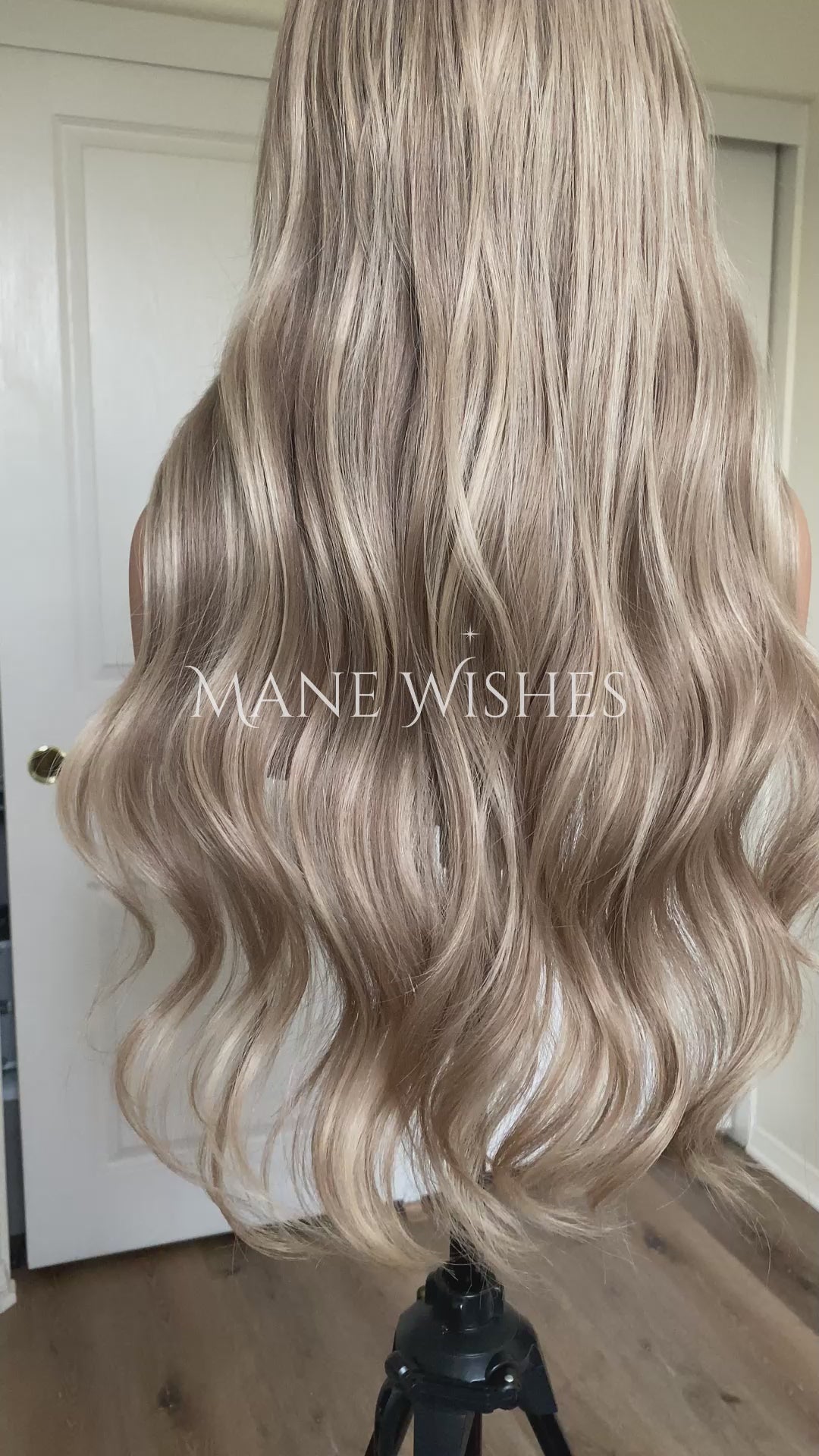 Blonde wig on a mannequin head with 'Mane Wishes' branding against a white door background.