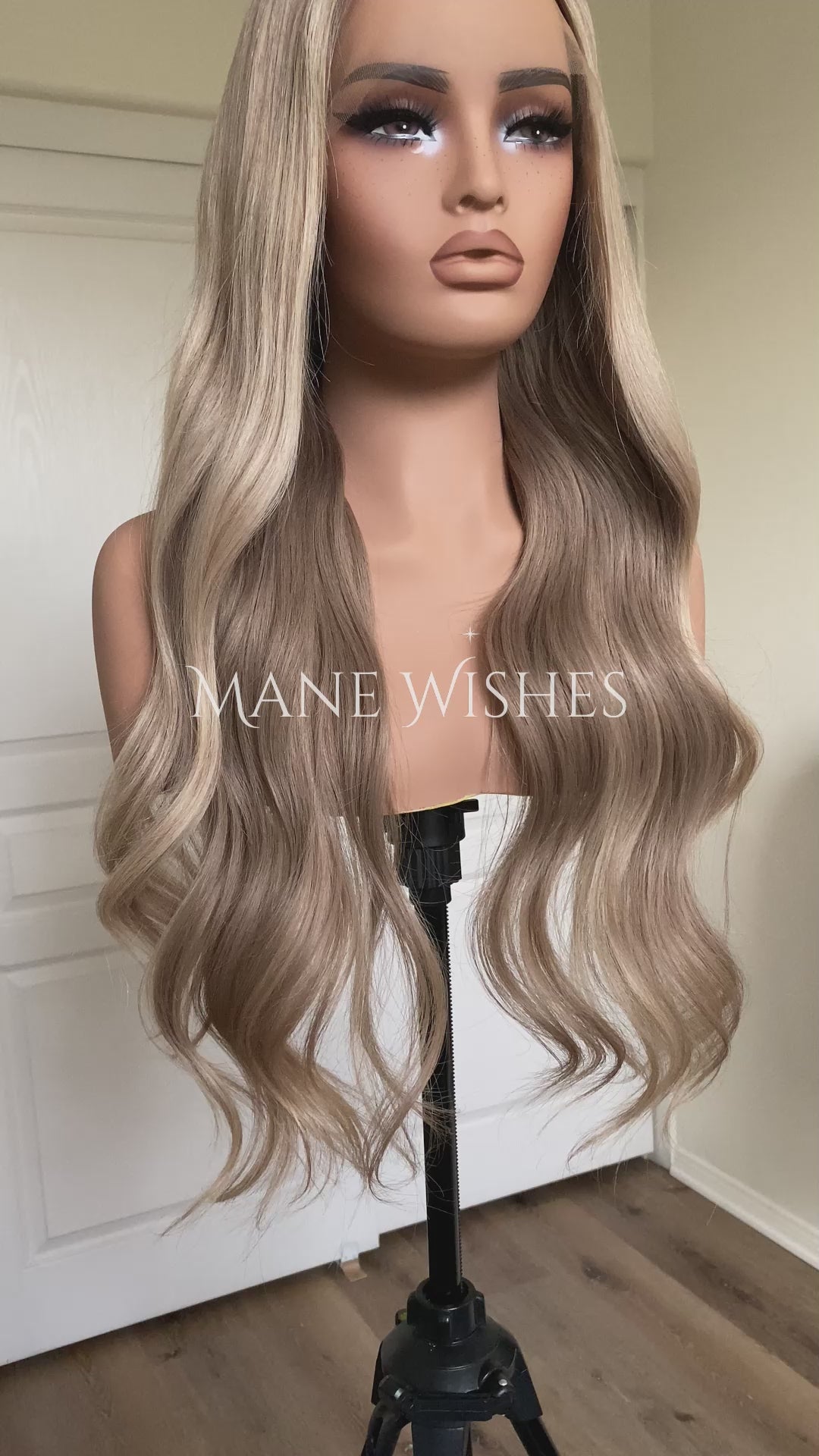 Blonde wig on a mannequin head with 'Mane Wishes' branding against a white door background.