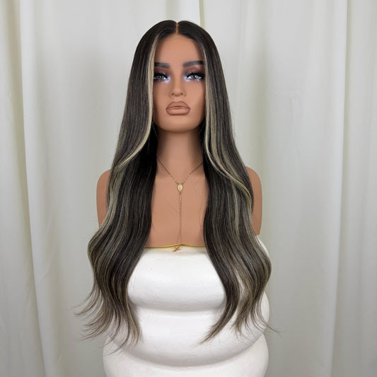 Mannequin head with a long, wavy, gray-to-black wig against a white curtain background.