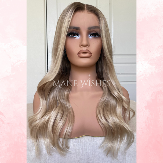 Mannequin head with blonde wig on a soft pink and white background, featuring the brand 'Mane Wishes'.