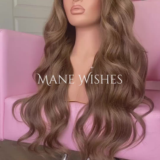 Mannequin head with long brown wig on a pink chair, branded 'Mane Wishes'.